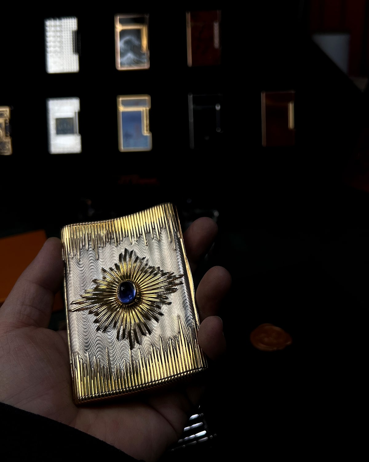 Gold starburst vintage lighter held for close inspection